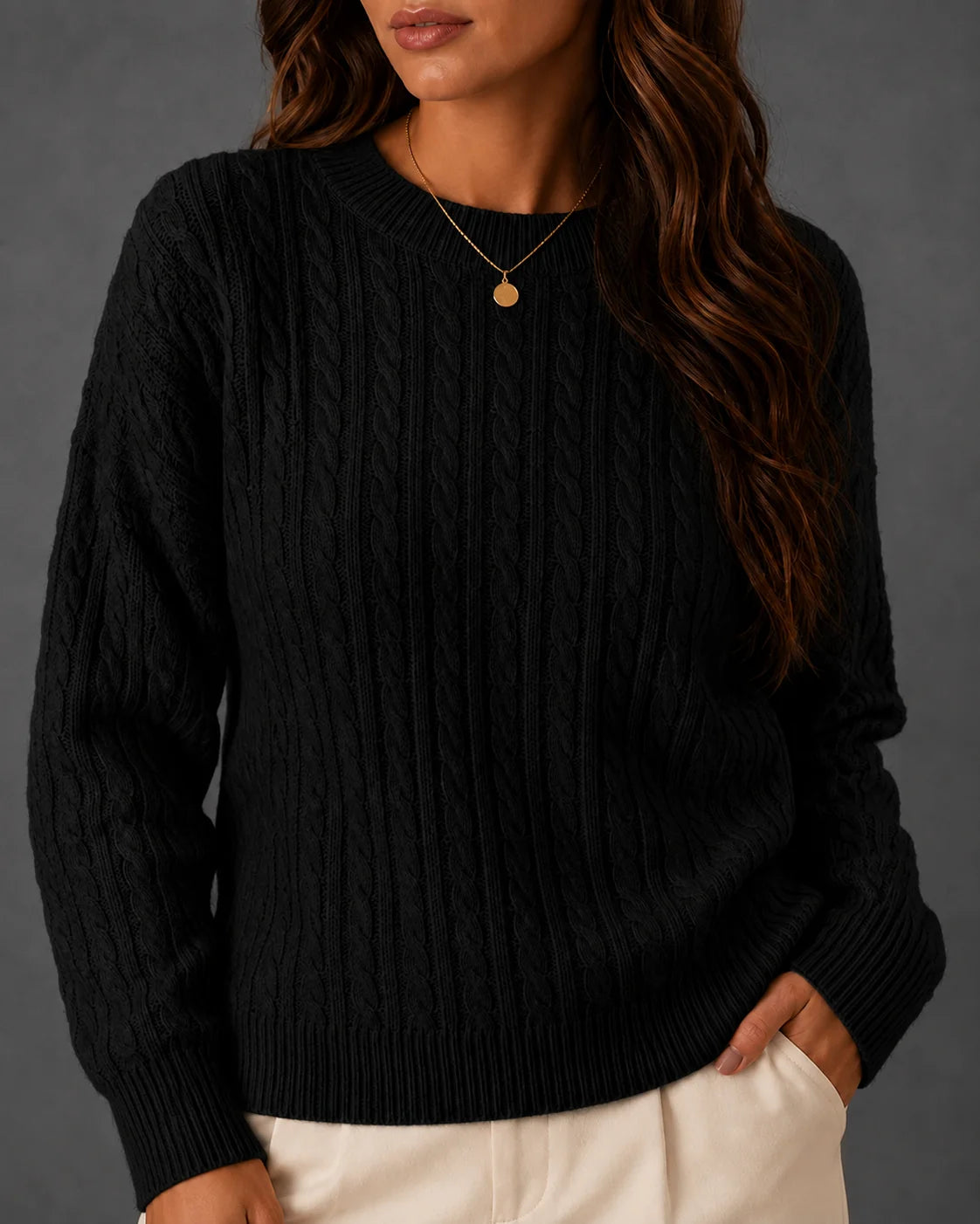 Woman wearing a black cable-knit crewneck sweater