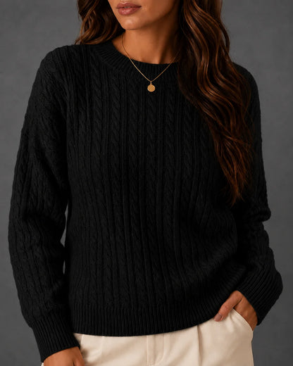 Woman wearing a black cable-knit crewneck sweater