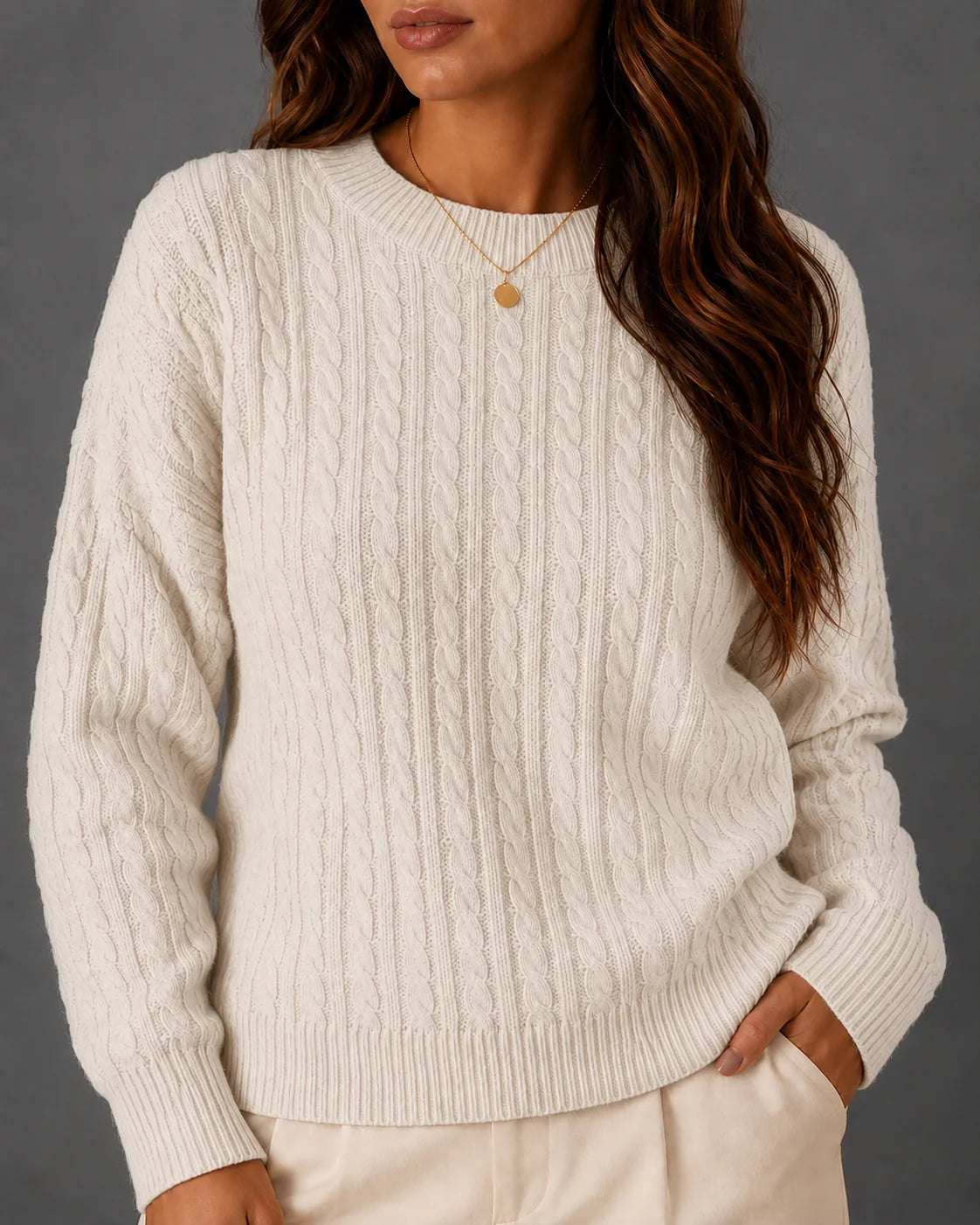 Woman wearing a cream cable-knit crewneck sweater