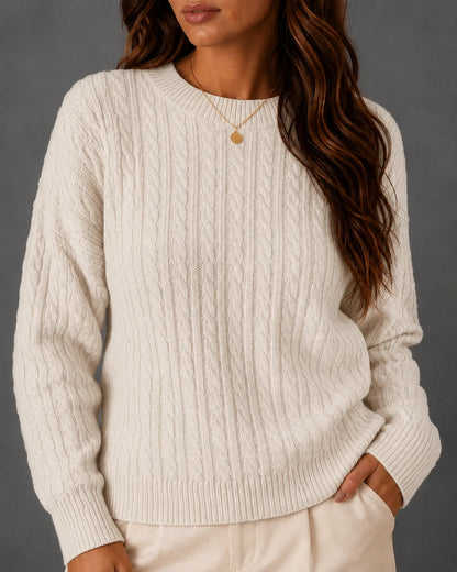 Woman wearing a cream cable-knit crewneck sweater