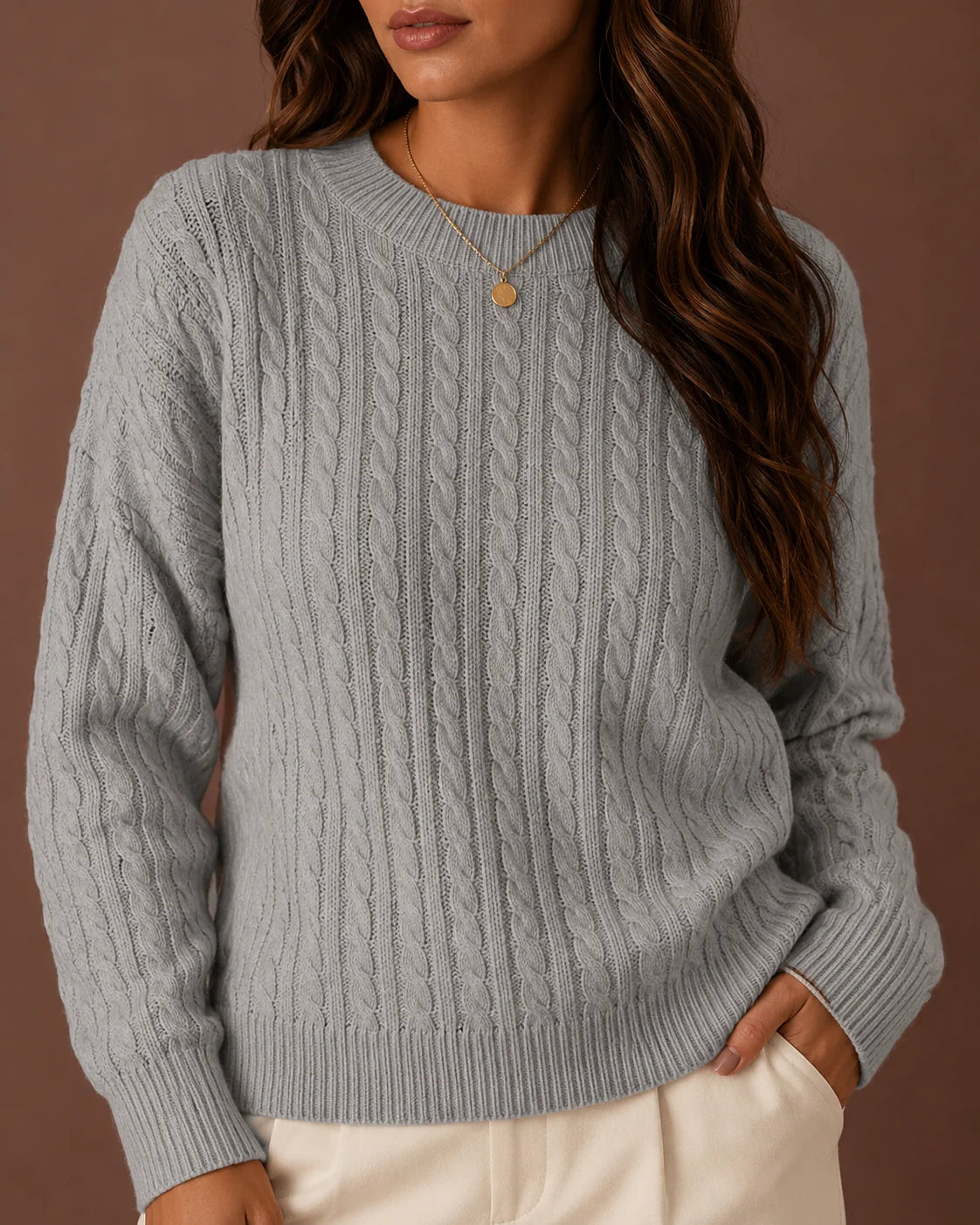 Woman wearing a grey cable-knit crewneck sweater