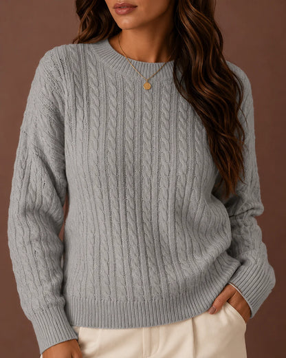 Woman wearing a grey cable-knit crewneck sweater