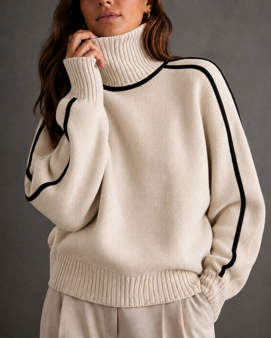 woman wearing a cream-colored ribbed knit turtleneck sweater with black contrast piping along the shoulders and sleeves