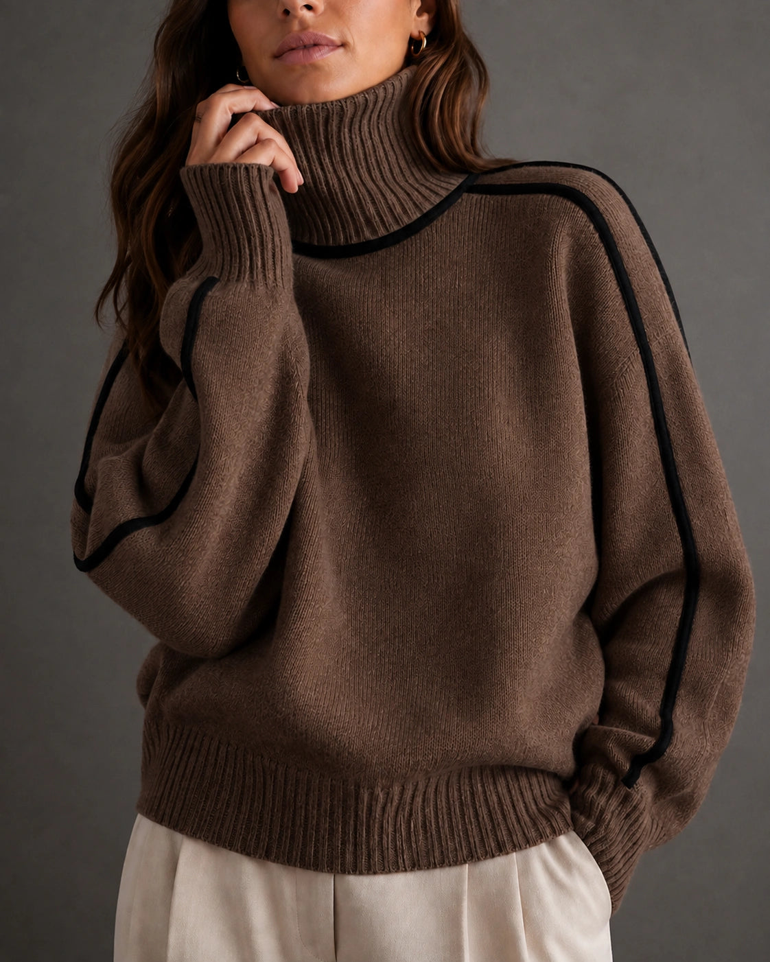 woman wearing a brown ribbed turtleneck sweater with black piping along the shoulders and sleeves