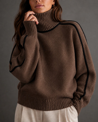 woman wearing a brown ribbed turtleneck sweater with black piping along the shoulders and sleeves