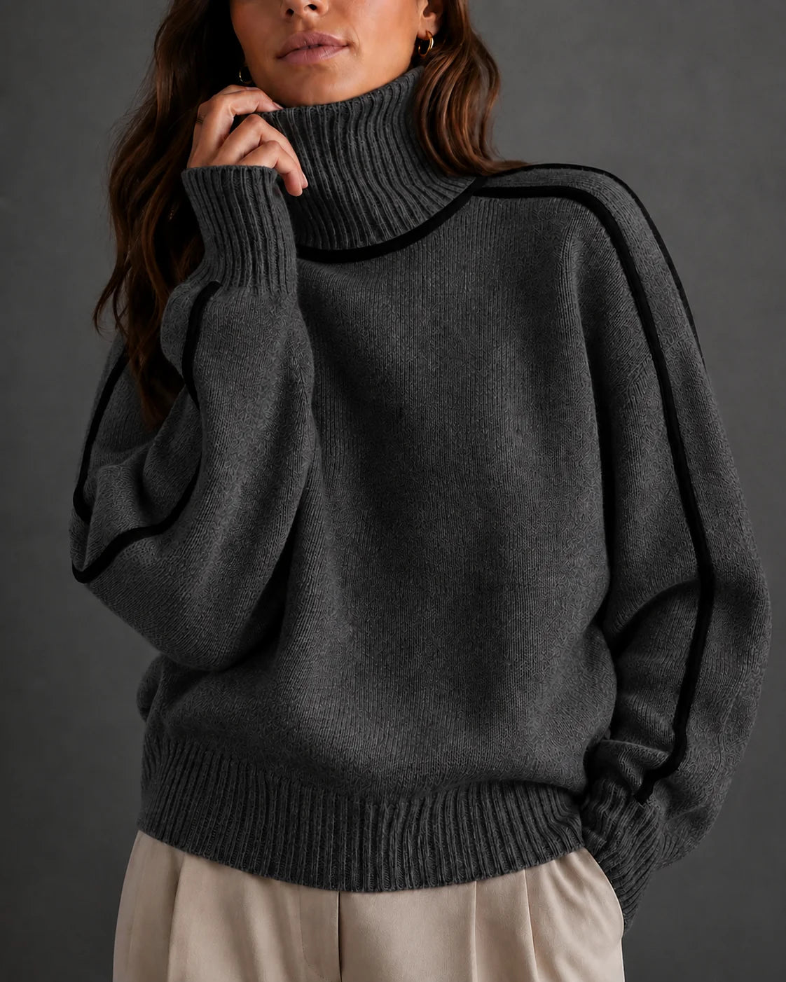 woman wearing a dark gray ribbed turtleneck sweater with black contrast piping along the shoulders and sleeves